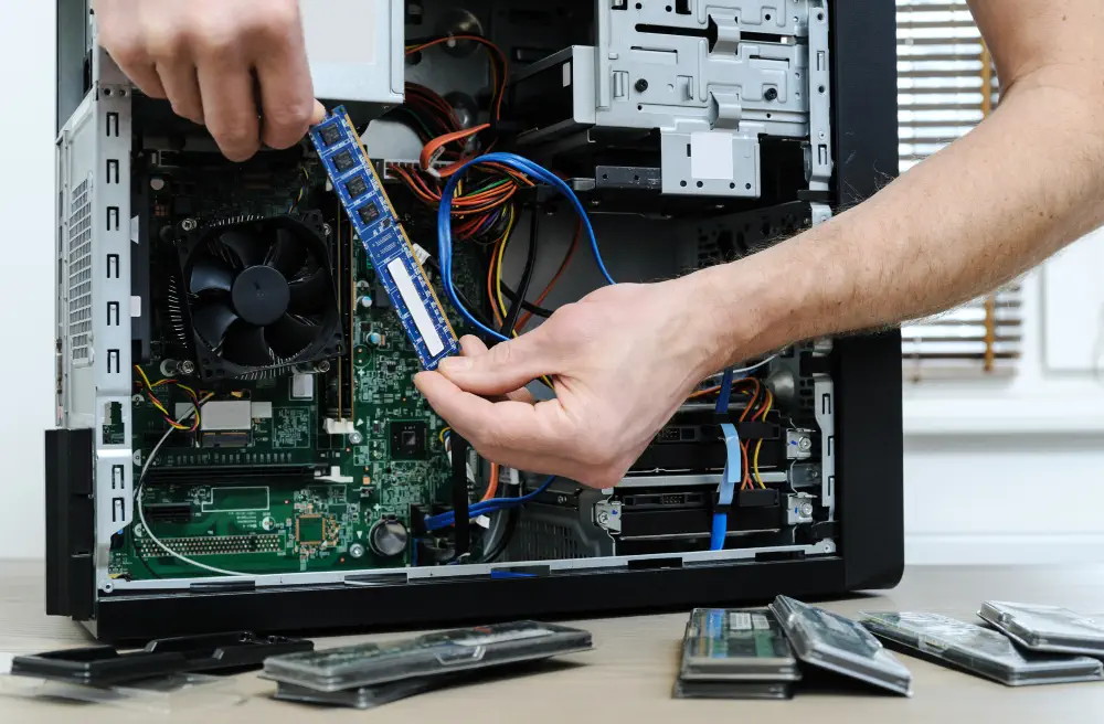 Technician installing RAM in desktop computer for network infrastructure upgrade.